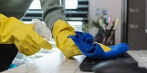 A Company's Cleaning Lady Is Diligently Cleaning The Executive's Office, The Cleaning Lady Wears Rubber Gloves To Prevent Irritation Form Chemicals While Cleaning