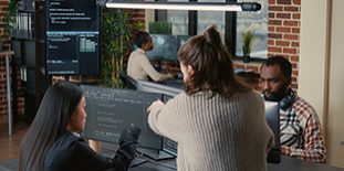 Software Programer Pointing Pencil At Source Code On Computer Screen Explaining Algorithm To Coworker